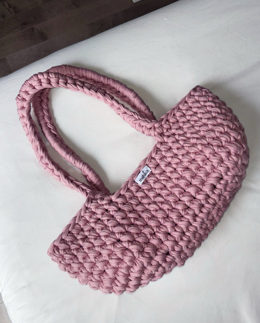 Pink woven crocheted bag on a white surface