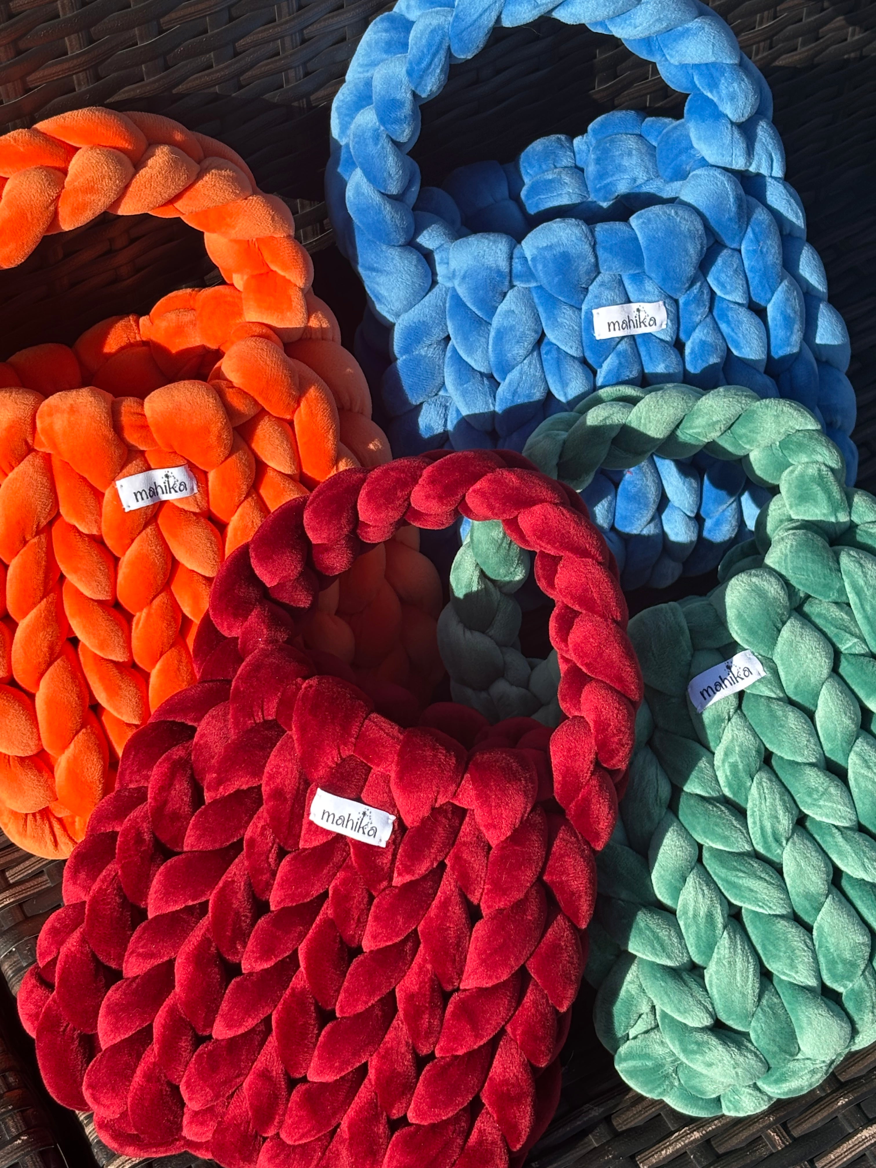 Colorful braided dog toys in blue, green, red, and orange on a dark surface.