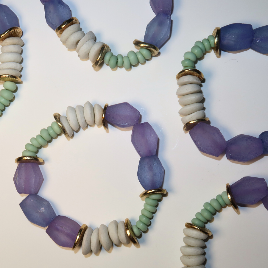 Three beaded bracelets with purple, green, and white beads on a light background